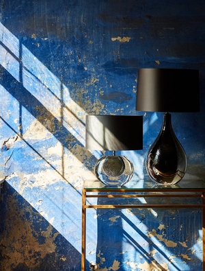 Blue distressed wall with black lamps on golden table
